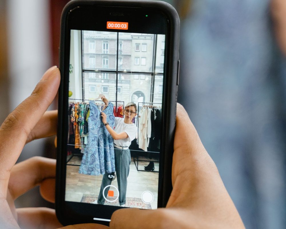 縦型の動画を撮るスマートフォンを、両手で持つ手元